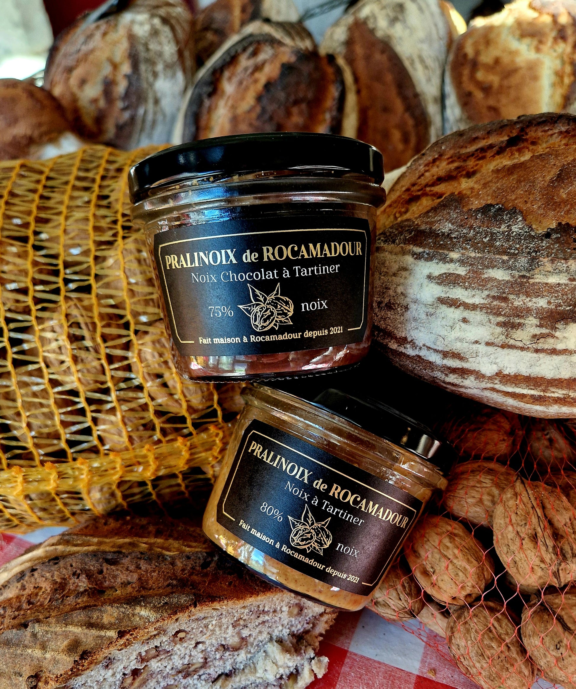 Jars of Pralinoix de Rocamadour nestled in bags of walnuts and freshly baked bread 